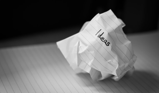 black and white photograph of scrunched up ball of paper with ideas written on it