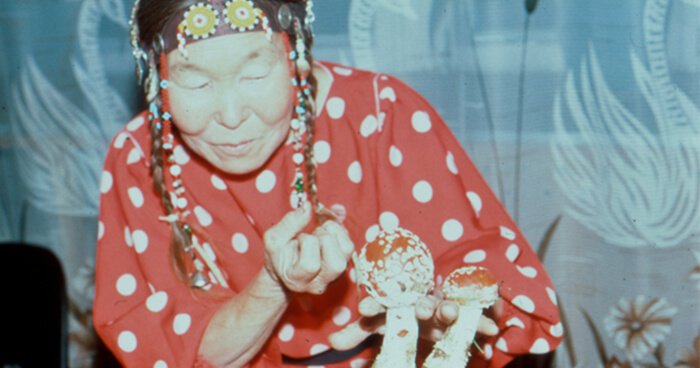 Siberian shaman woman in red polka dot outfit with flay agaric mushrooms